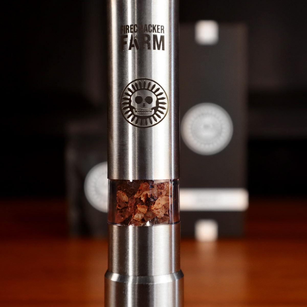 A stainless steel Apocalypto push grinder filled with coarse sea salt, with visible branding and design elements.